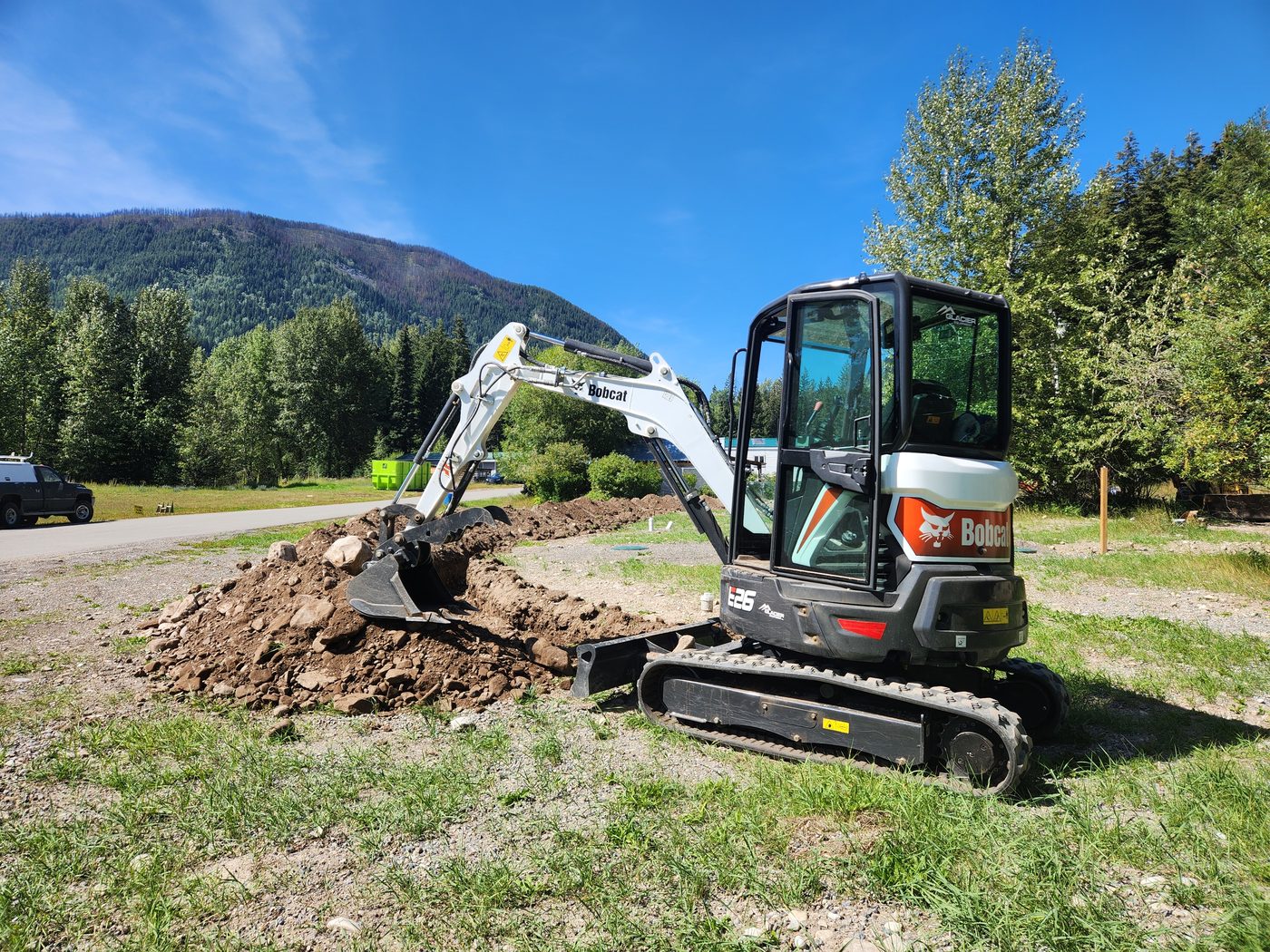 Mini excavator digging test excavation on a rural BC property