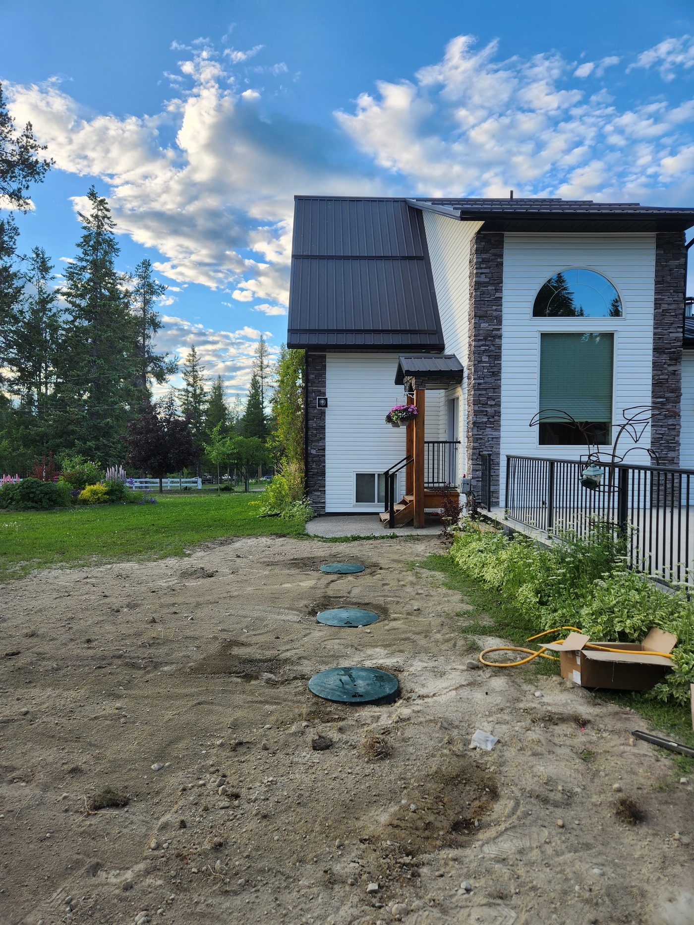 Completed septic system replacement with tank risers at final grade beside a home